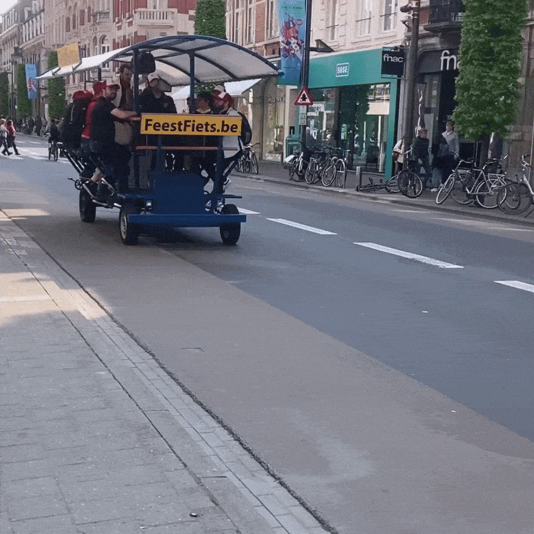Bierfiets (feestfiets) die heen en weer rijdt in centrumstad, Stuk of 10 jonge mannen trappen op pedalen en drinken bier terwijl een van hen het gevaarte bestuurt.
